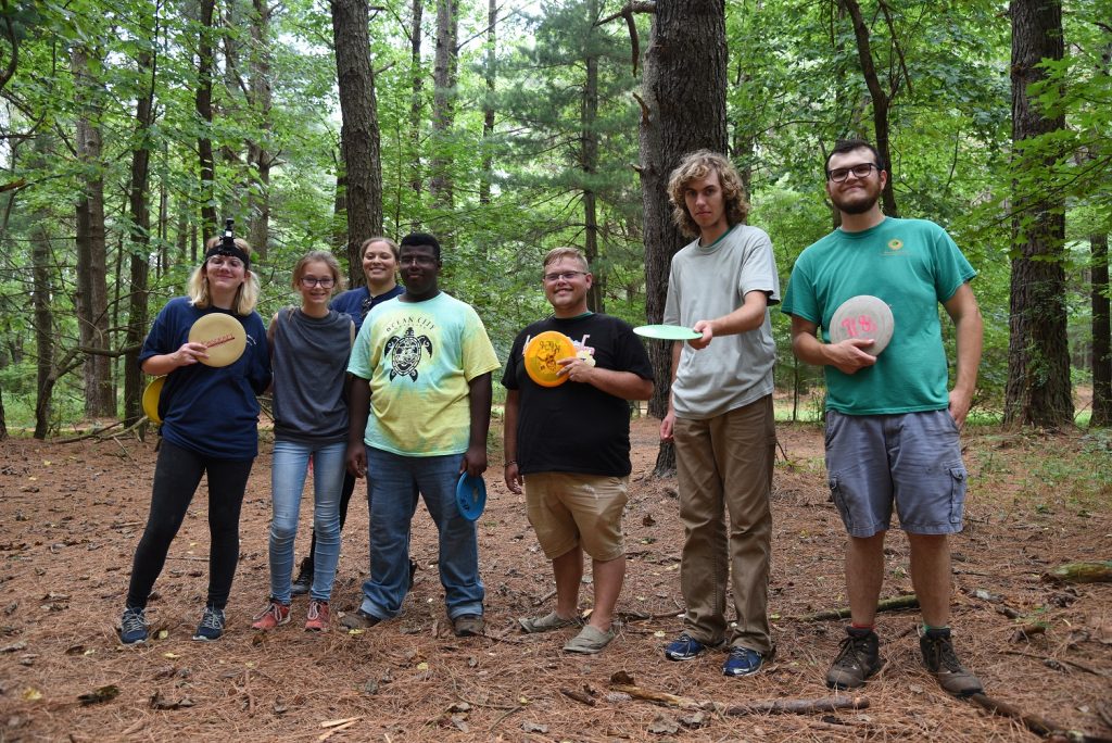 A group of people pose while playing disc golf.